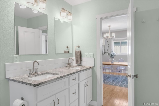 4933 Grove St, Denver, CO 80221 - bathroom featuring a chandelier, wood finished floors, and double vanity