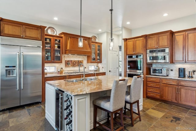 kitchen with brown cabinetry, decorative backsplash, glass insert cabinets, a sink, and appliances with stainless steel finishes