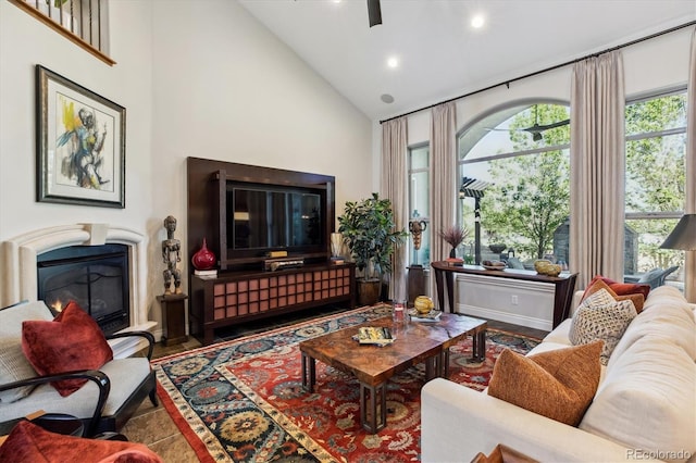 living room with a glass covered fireplace, high vaulted ceiling, a ceiling fan, and recessed lighting