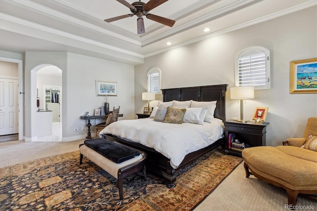 bedroom featuring ornamental molding, light carpet, recessed lighting, a raised ceiling, and arched walkways