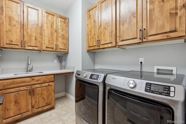 laundry area with washing machine and clothes dryer, cabinet space, a sink, baseboards, and light tile patterned flooring