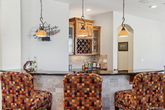 bar featuring backsplash, recessed lighting, pendant lighting, and a bar