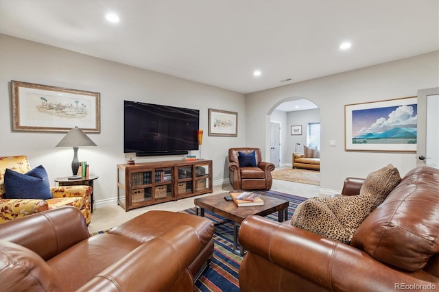 carpeted living room featuring baseboards, arched walkways, and recessed lighting
