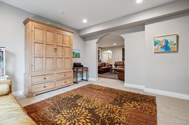 interior space featuring baseboards, arched walkways, recessed lighting, and light carpet