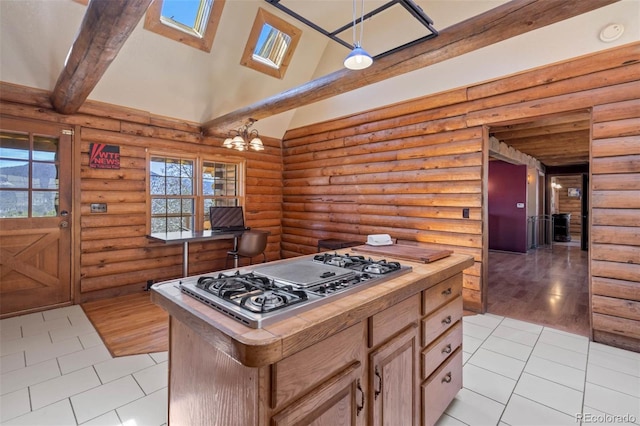 660 Wagon Wheel Rd, Guffey, CO 80820 - kitchen featuring stainless steel gas stovetop, light tile patterned floors, rustic walls, a center island, and a skylight