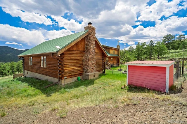 660 Wagon Wheel Rd, Guffey, CO 80820 - view of home's exterior featuring a chimney, log siding, a metal roof, and a storage shed