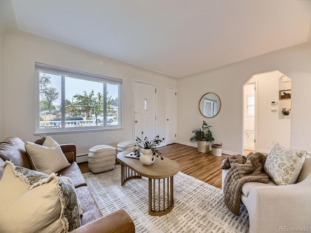 5703 Ammons St, Arvada, CO 80002 - living area featuring arched walkways, wood finished floors, baseboards, and a baseboard heating unit