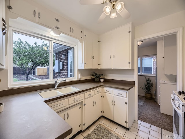 5703 Ammons St, Arvada, CO 80002 - kitchen with gas range gas stove, a sink, light tile patterned floors, white cabinets, and dark countertops