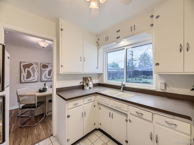 5703 Ammons St, Arvada, CO 80002 - kitchen featuring a sink, dark countertops, white cabinets, light wood finished floors, and freestanding refrigerator