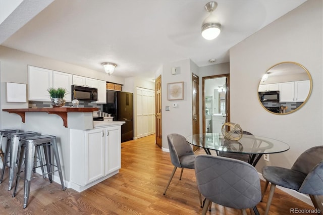 840 S Vance St Unit A, Lakewood, CO 80226 - kitchen featuring light wood finished floors, black appliances, a breakfast bar, and white cabinetry