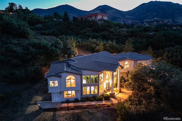 rear view of property with a mountain view, a forest view, and stucco siding