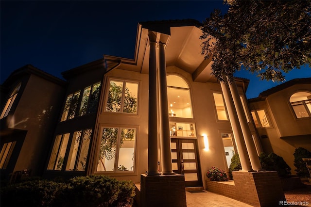 back of house at night featuring stucco siding