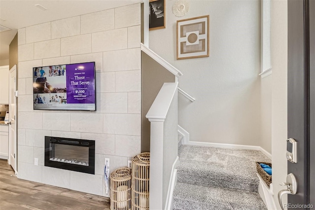 stairway featuring a tiled fireplace and wood-type flooring