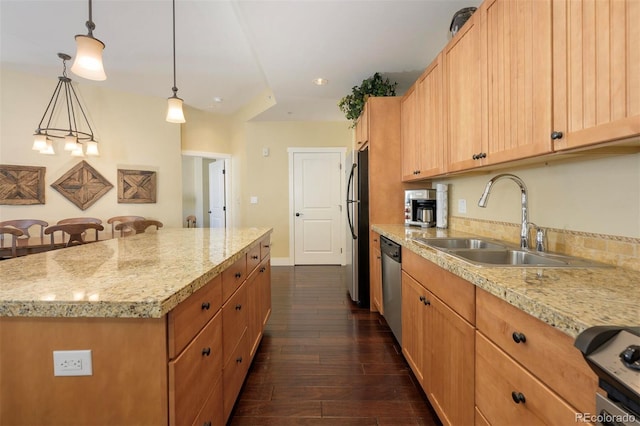 kitchen featuring dark wood finished floors, a center island, stainless steel appliances, pendant lighting, and a sink