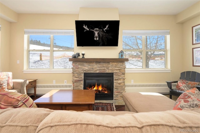 living room with radiator heating unit, baseboards, wood finished floors, and a stone fireplace