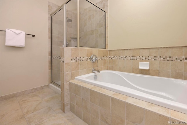 full bathroom featuring a shower stall, a bath, and baseboards