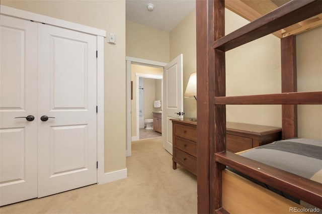 bedroom featuring light carpet, a closet, and baseboards