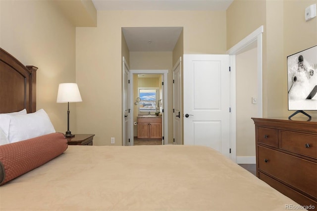 bedroom with baseboards and connected bathroom