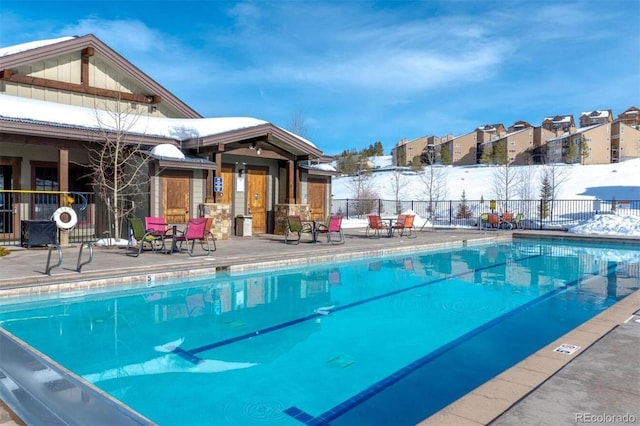 community pool with a patio area and fence