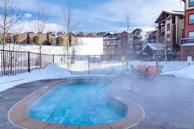 snow covered pool with a fenced backyard and a residential view