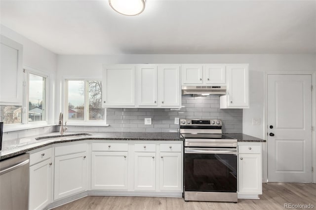 kitchen with white cabinetry, sink, dark stone countertops, stainless steel appliances, and light hardwood / wood-style flooring