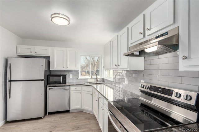 kitchen with sink, light hardwood / wood-style flooring, appliances with stainless steel finishes, decorative backsplash, and white cabinets