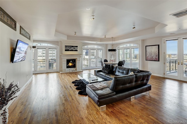 living room with hardwood / wood-style flooring, french doors, and a raised ceiling