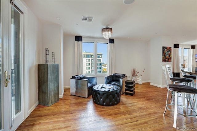 sitting room with light wood-style floors, a chandelier, visible vents, and baseboards