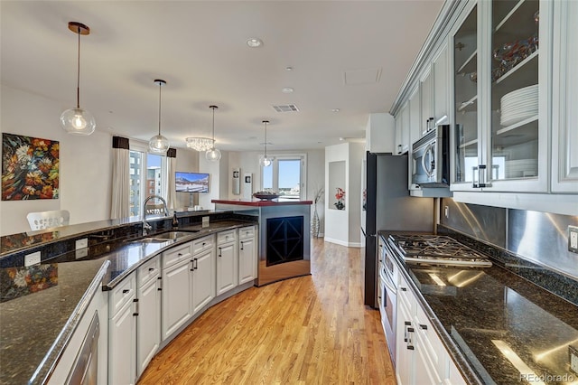 kitchen featuring appliances with stainless steel finishes, sink, white cabinets, and decorative light fixtures