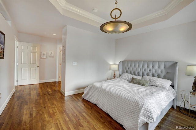 bedroom featuring dark wood-type flooring, ornamental molding, and a tray ceiling