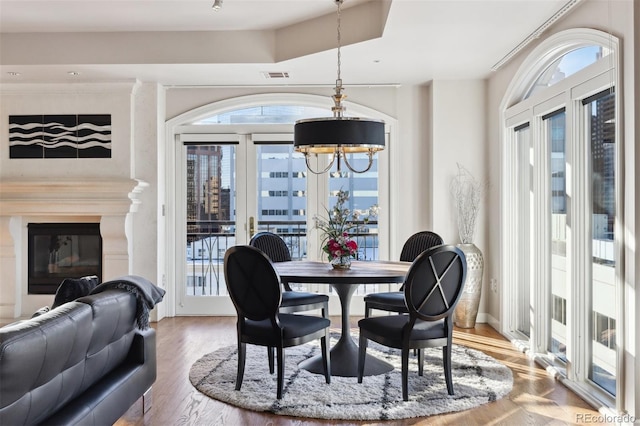 dining room featuring plenty of natural light, visible vents, a chandelier, and a glass covered fireplace