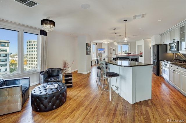 kitchen with stainless steel appliances, dark countertops, a chandelier, and visible vents