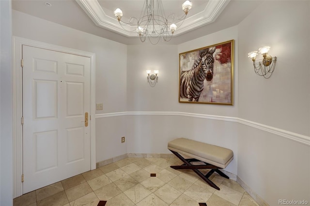 entryway with a raised ceiling, a notable chandelier, and baseboards