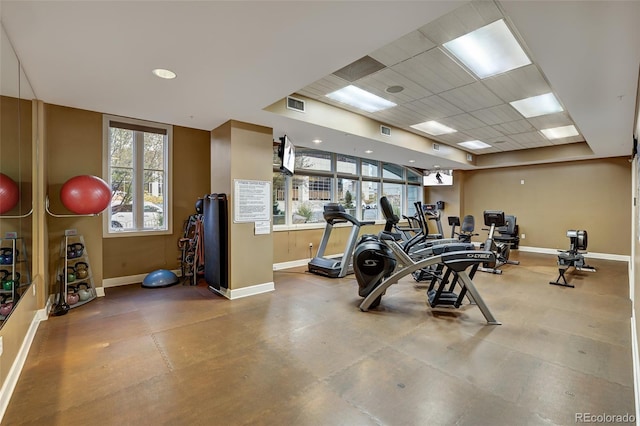 exercise room featuring a paneled ceiling, visible vents, and baseboards