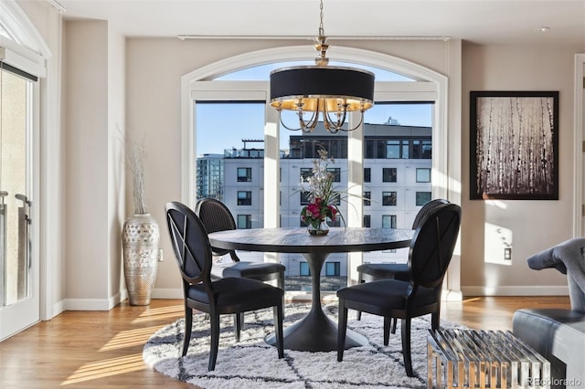 dining room featuring baseboards, light wood finished floors, and an inviting chandelier