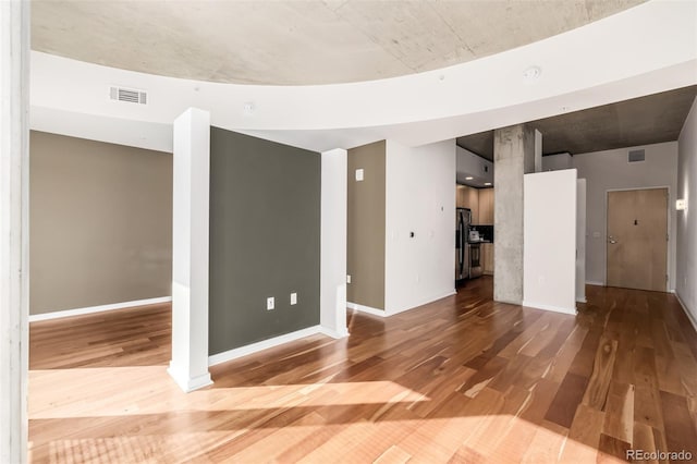 unfurnished living room with visible vents, baseboards, and wood finished floors