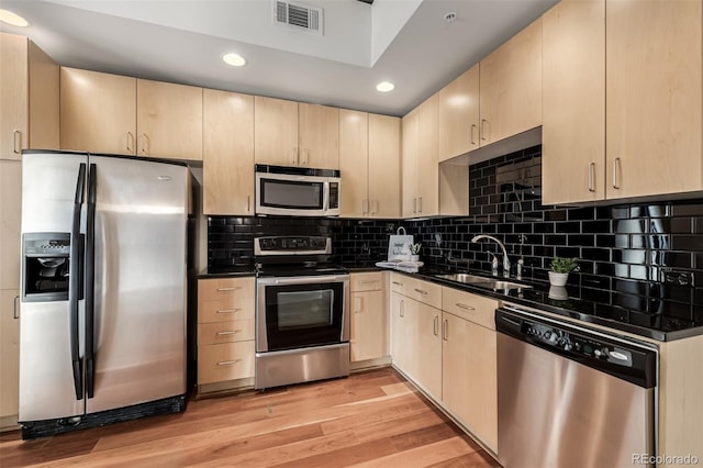 kitchen with light brown cabinetry, light wood-type flooring, stainless steel appliances, and sink