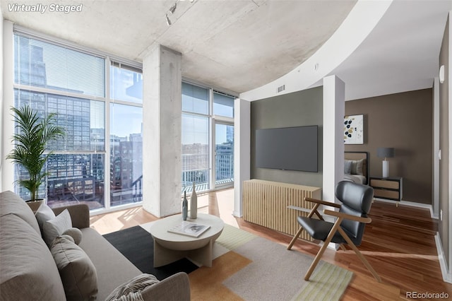 living room with radiator, hardwood / wood-style floors, and a wall of windows