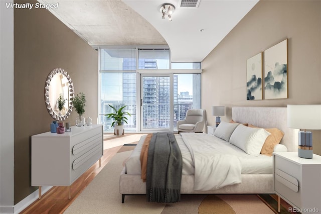 bedroom featuring a wall of windows, visible vents, a city view, and wood finished floors