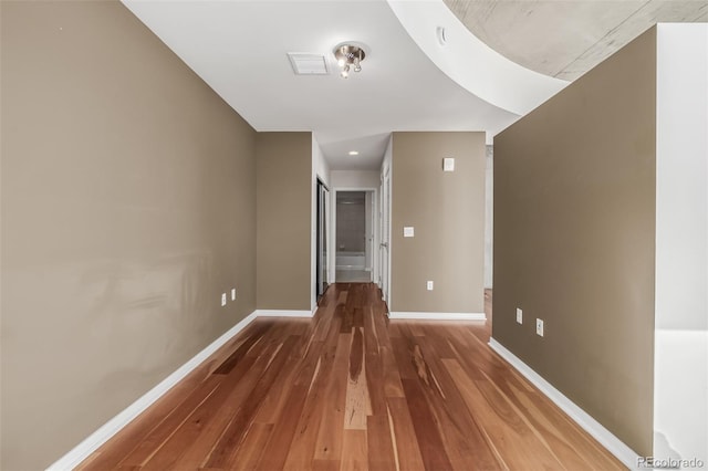 hall with visible vents, baseboards, and wood finished floors