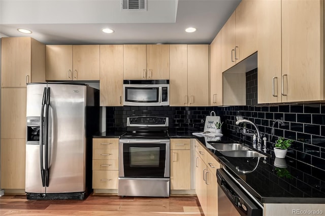 kitchen featuring a sink, appliances with stainless steel finishes, light brown cabinets, and visible vents