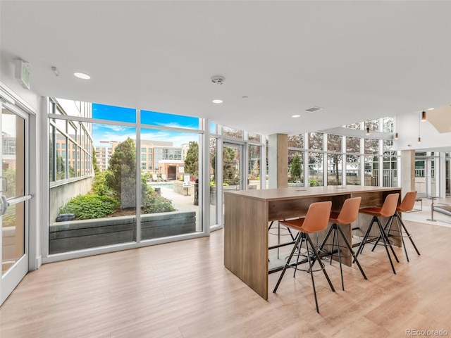 bar featuring light wood-style floors, expansive windows, visible vents, and recessed lighting