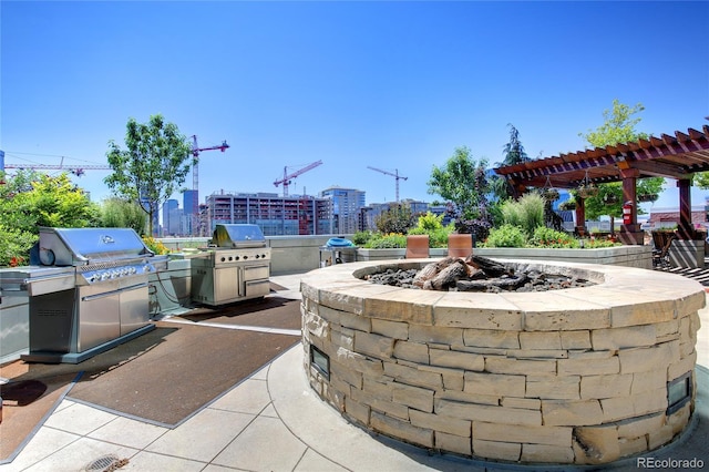 view of patio featuring a view of city, grilling area, an outdoor kitchen, and a pergola