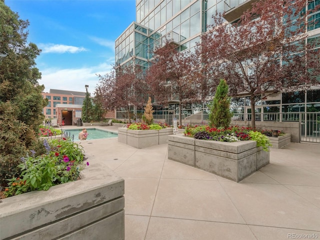 view of property's community with a patio area, a garden, fence, and a pool