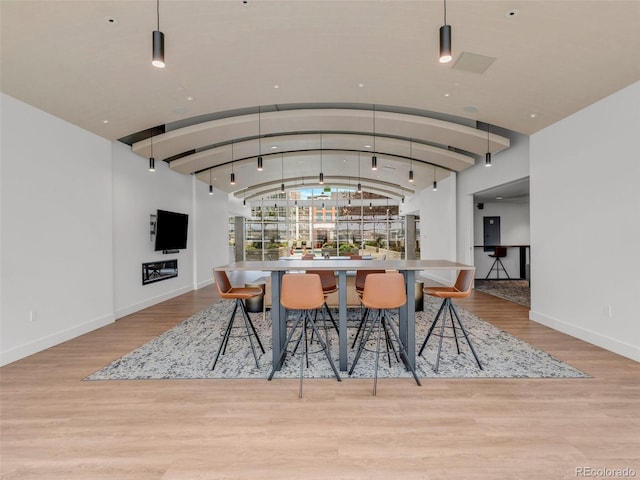 dining space featuring lofted ceiling, baseboards, and wood finished floors