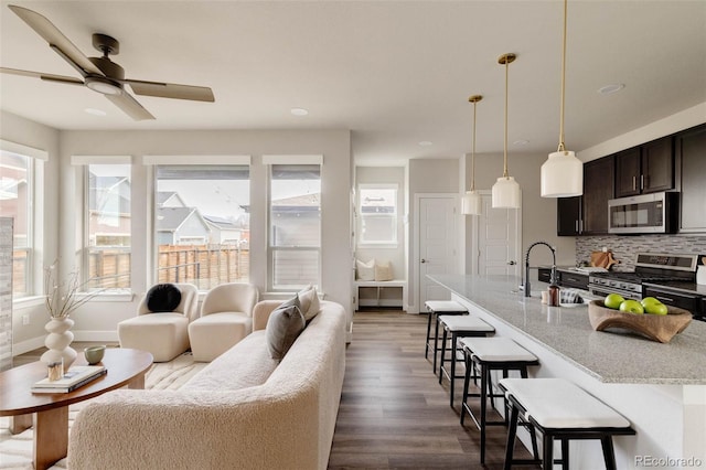 living room with dark wood-style floors, baseboards, and a ceiling fan