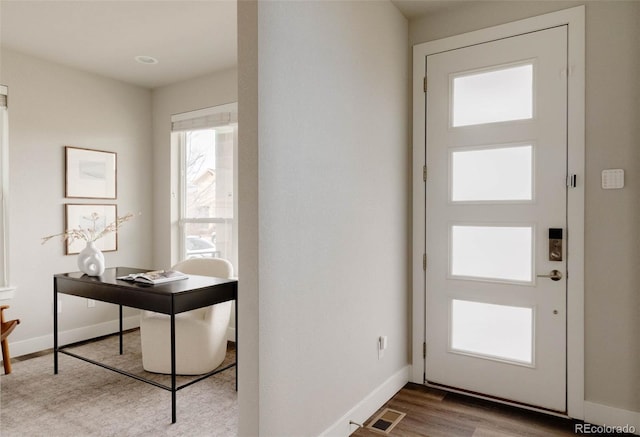 foyer entrance with visible vents, baseboards, and wood finished floors