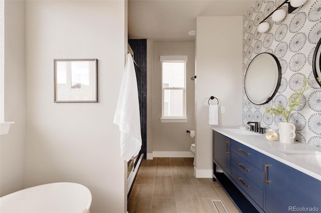 bathroom with double vanity, toilet, a sink, a shower with curtain, and baseboards