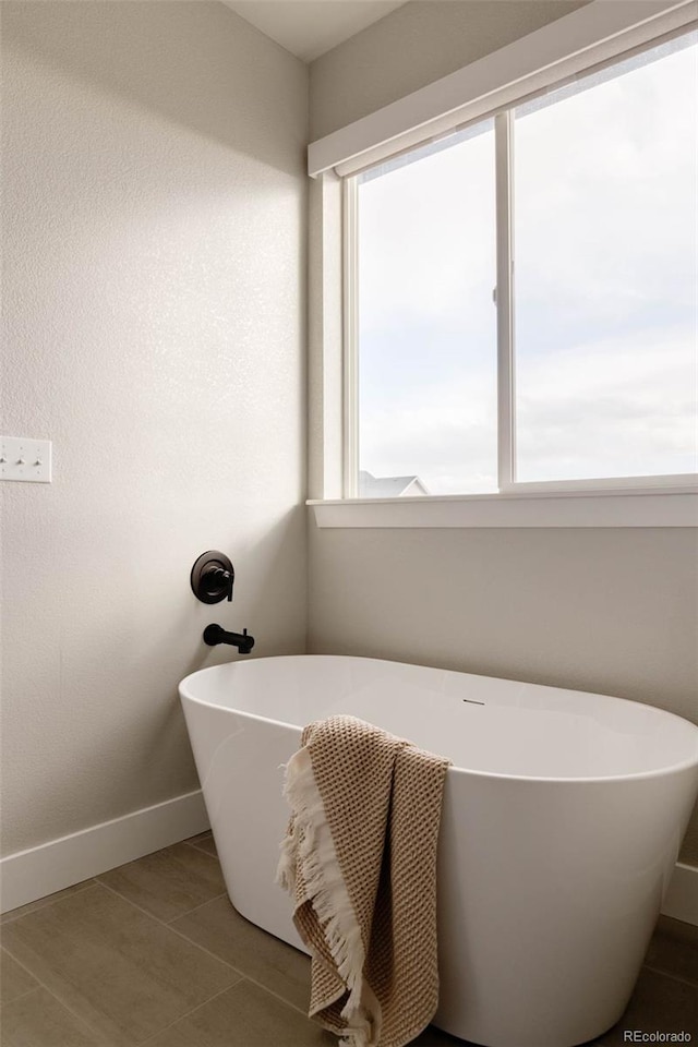 bathroom with a freestanding tub and baseboards