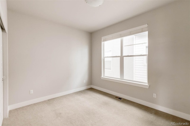 carpeted spare room with visible vents and baseboards